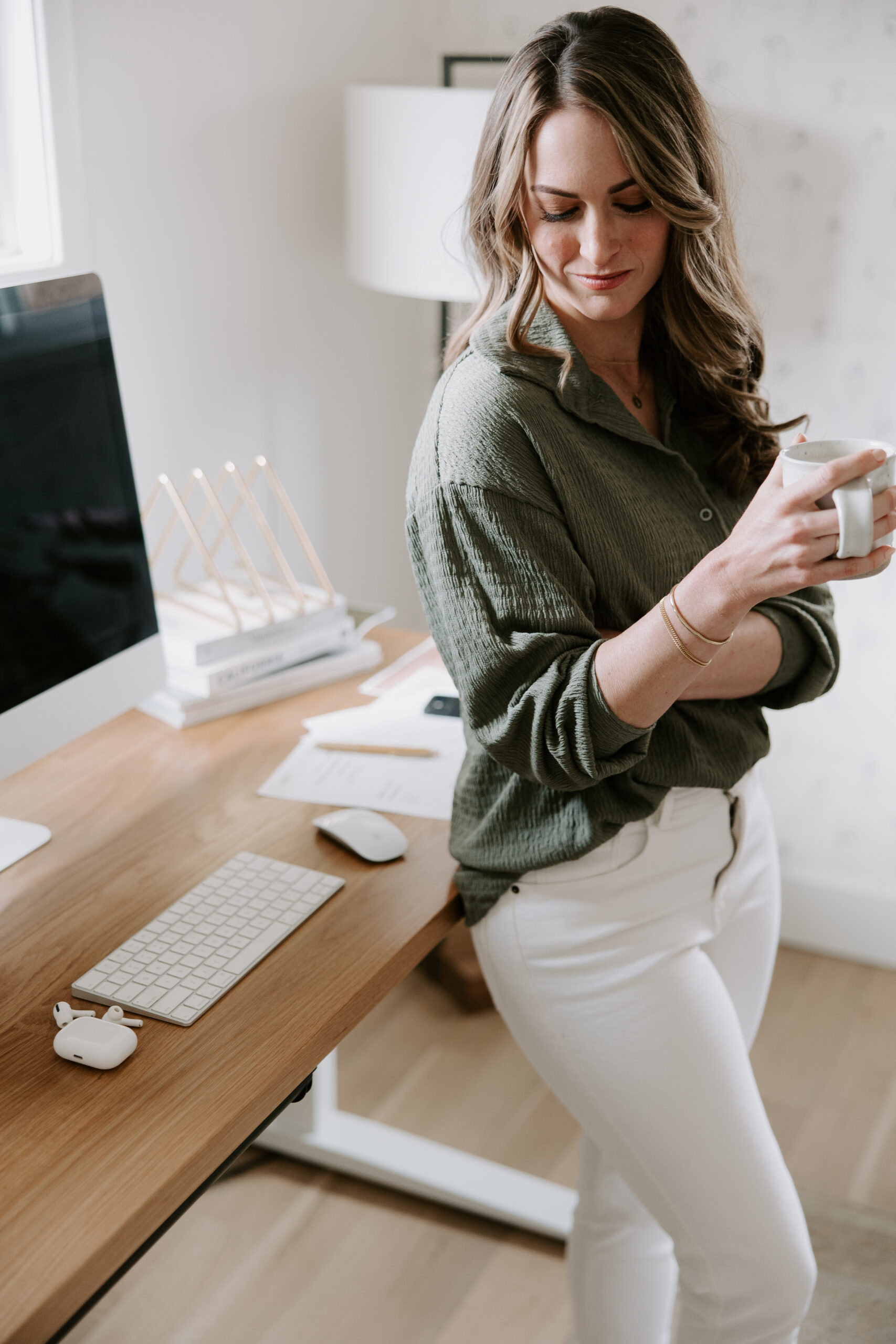 A website copywriter leaning on her desk holding a coffee mug